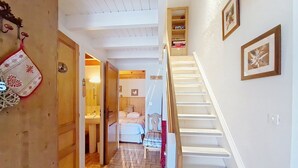 A staircase leading to a bedroom with a bed, a wooden door, and a shelf with books. - Chalet Madeline MD25 SUN & VIEW 6 pers. (Châtel)