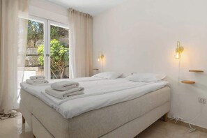 A clean, modern bedroom with a large bed, two bedside tables, and a view of greenery outside. - Riviera del Sol rooftop by Costarentals - Ref 45 (Urbanización Riviera Sol)