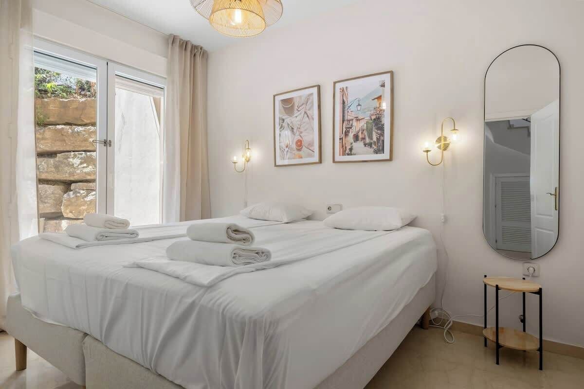 Ein Hotelzimmer mit einem großen Bett, zwei Wandleuchten, einem Spiegel und zwei gerahmten Bildern.
