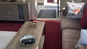 A compact living space with a kitchenette, a dining area, and a seating area with a sofa and a coffee table. - Relaxing Lodge In The Heart Of Northumberland (Felton)