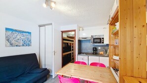 Une cuisine compacte équipée d’un four à micro-ondes, d’une machine à café et de meubles de rangement en bois.