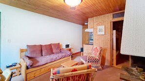 A cozy room with a wooden sofa, a small table, and a wicker chair.