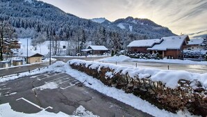 A snow-covered parking lot with buildings and a mountain in the background. - Orchidée OD8 NATURE & TELECABINE 4 pers. (Châtel)