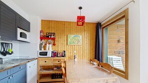 Una cocina compacta con una mesa de madera, un microondas y diversos utensilios de cocina.