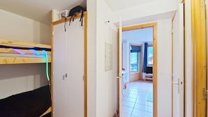 Una habitación con literas, un armario y una puerta que da a un pasillo.
