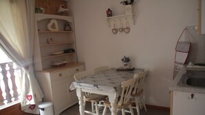 A small dining area with a table and chairs, a white cabinet, and a shelf with decorative items. - Orchidée OD5 NATURE & TELECABINE 4 pers. (Châtel)
