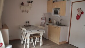 A compact kitchen with a dining table, chairs, a microwave, and a sink. - Orchidée OD5 NATURE & TELECABINE 4 pers. (Châtel)