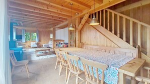 A wooden interior with a dining table, chairs, and a staircase.