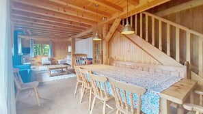 A wooden interior with a dining table, chairs, and a staircase.