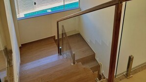 A wooden staircase with a glass railing leading to a balcony with a view of a beach and the sea. - Humaita Pousada (Itacaré)