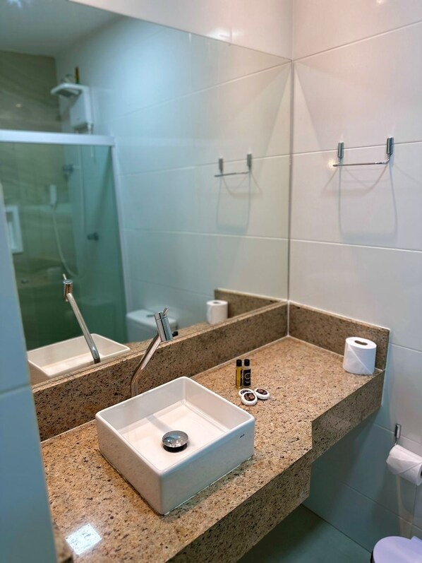 A modern bathroom with a granite countertop, a white sink, and a mirror. - Humaita Pousada (Itacaré)