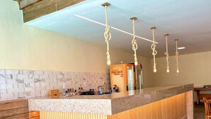 A modern kitchen with a central island, wooden ceiling beams, and pendant lights. - Humaita Pousada (Itacaré)