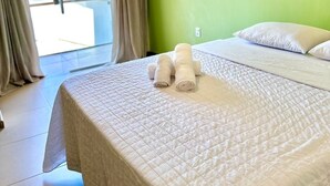 A hotel room with a bed, a hanging light fixture, and a view of the outside. - Humaita Pousada (Itacaré)