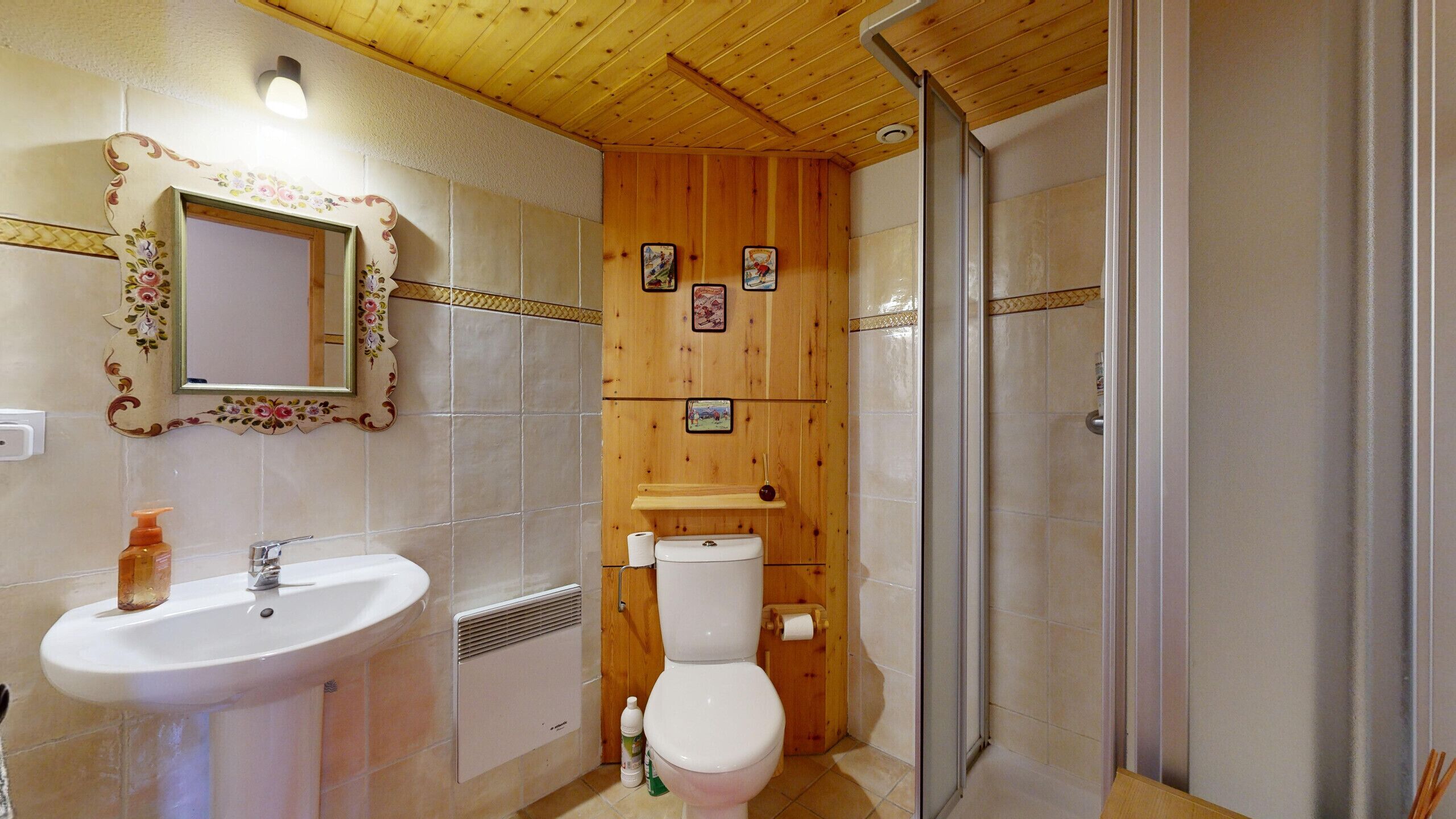 Une salle de bain avec un plafond en bois, un lavabo, des toilettes et un espace douche.