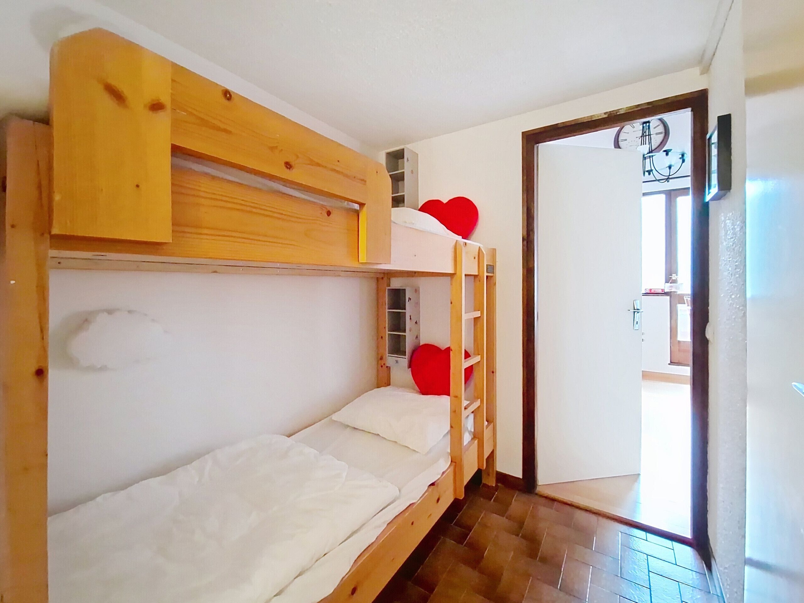 Camera con un letto a castello, una scala in legno e due decorazioni a forma di cuore rosso.