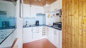 A compact kitchen with white cabinets, a built-in microwave, and a coffee maker. - Rhododendrons RD501 CENTER & TELECABINE 4 Pers. (Châtel)