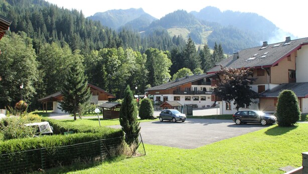 Zona residencial con casas, un estacionamiento y montañas al fondo.