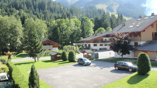 Zona residencial con casas, un coche y montañas al fondo.