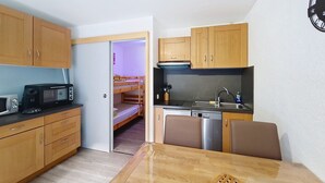 A compact kitchen with wooden cabinets, a microwave, a toaster, and a sink. - Portes Du Soleil PSB204 TELECABINE & MOUNTAIN 4 pe (Châtel)