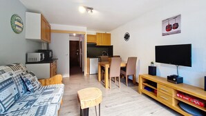 A compact living space with a sofa, a small dining table, a TV, and a kitchenette. - Portes Du Soleil PSB204 TELECABINE & MOUNTAIN 4 pe (Châtel)