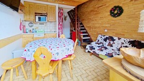 Cocina acogedora con armarios de madera, microondas y una mesa de comedor con sillas.