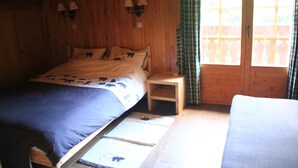 A wooden room with a bed, a nightstand, and a window with curtains.