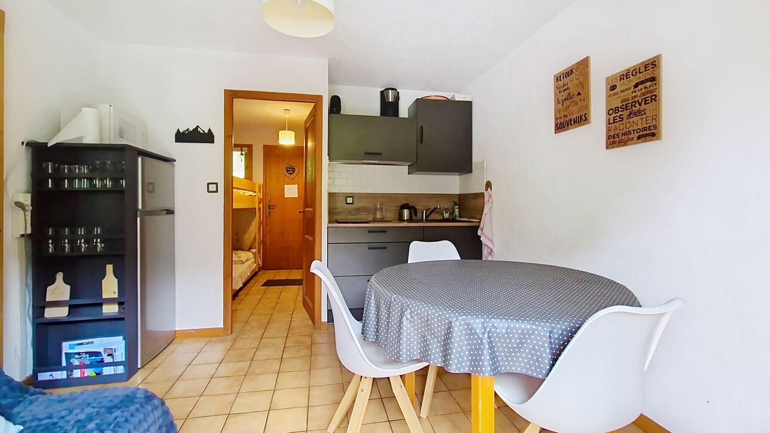 Un espacio habitable compacto con kitchenette, una zona de comedor con mesa redonda y un pequeño rincón de estar.