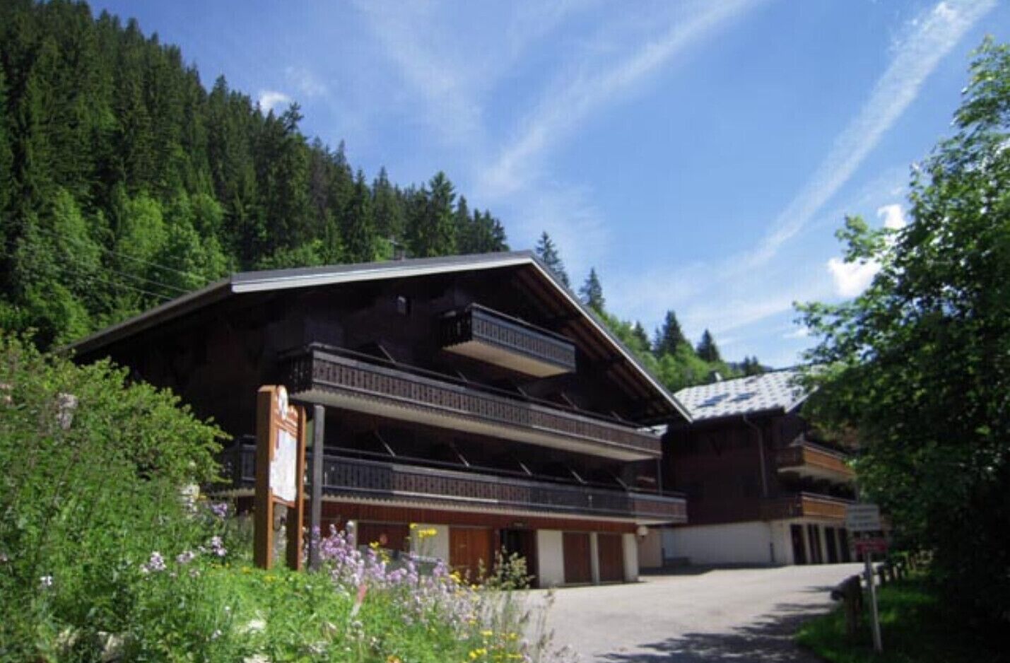 Een chalet met balkon, omringd door bos.