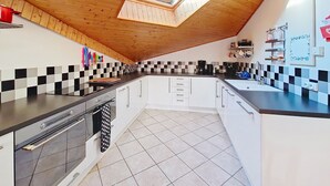 A kitchen with a sloped ceiling, a skylight, checkered backsplash, and modern appliances. - Myrtilles MR27 TELECABINE & NATURE 6 pers. (Châtel)