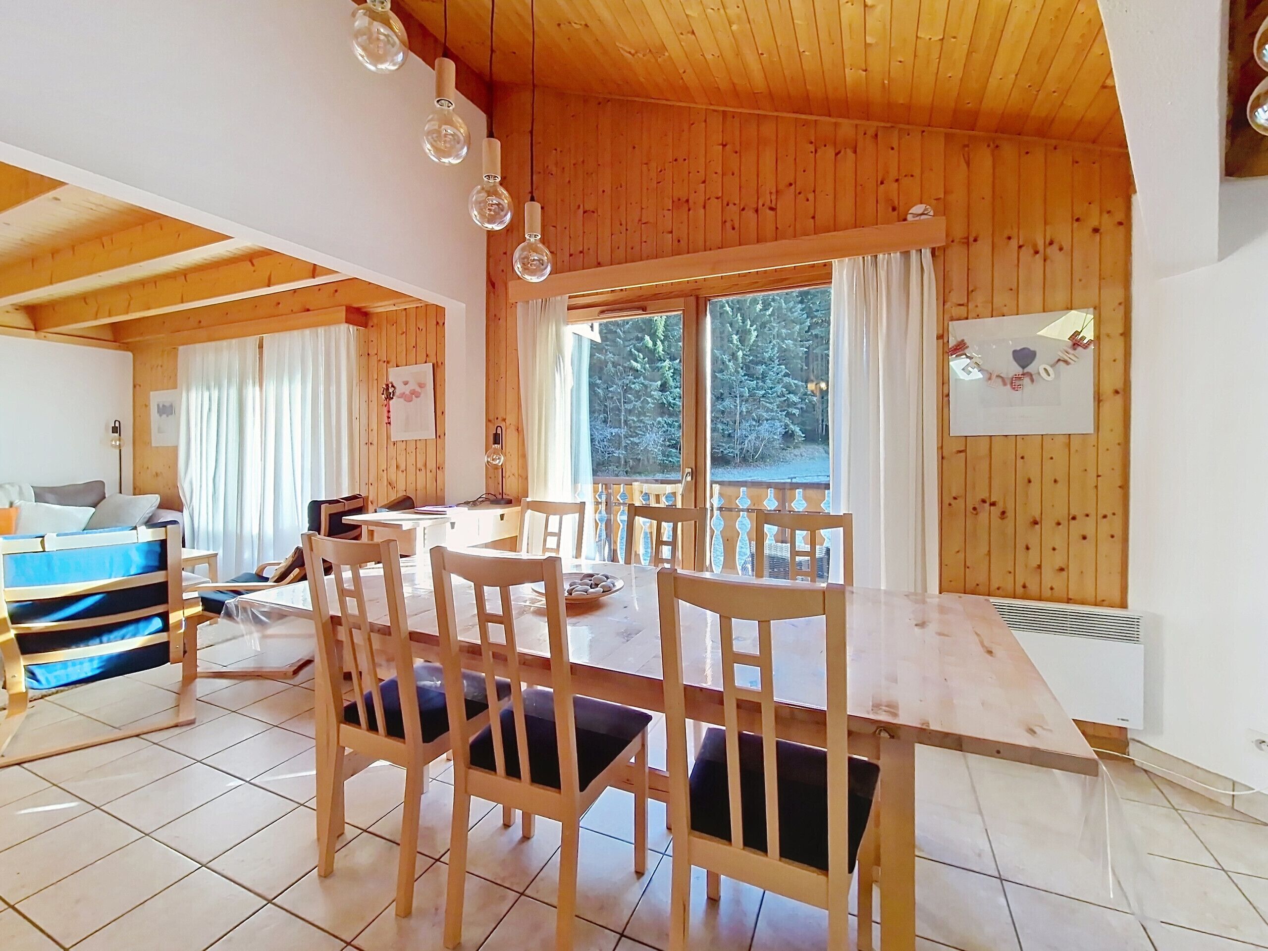 A wooden interior with a dining table, chairs, and a view of the outdoors.