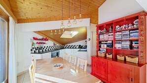 A modern kitchen with a wooden ceiling, a dining table with chairs, and a red cabinet with DVDs. - Myrtilles MR27 TELECABINE & NATURE 6 pers. (Châtel)