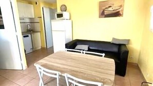 Un ambiente compatto con un tavolo da pranzo e sedie, un divano, un angolo cottura e una piccola cucina.