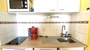Una cucina compatta con forno a microonde, lavello e lavatrice.