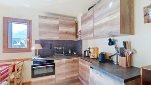 Eine moderne Küche mit Holzausstattung, einem Einbauofen, einer Kaffeemaschine und einem Fenster mit Aussicht.