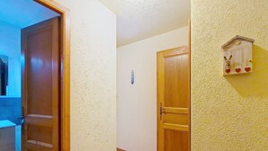 Ein Flur mit einer Holztür, einer kleinen Wanddekoration und einem gefliesten Boden.