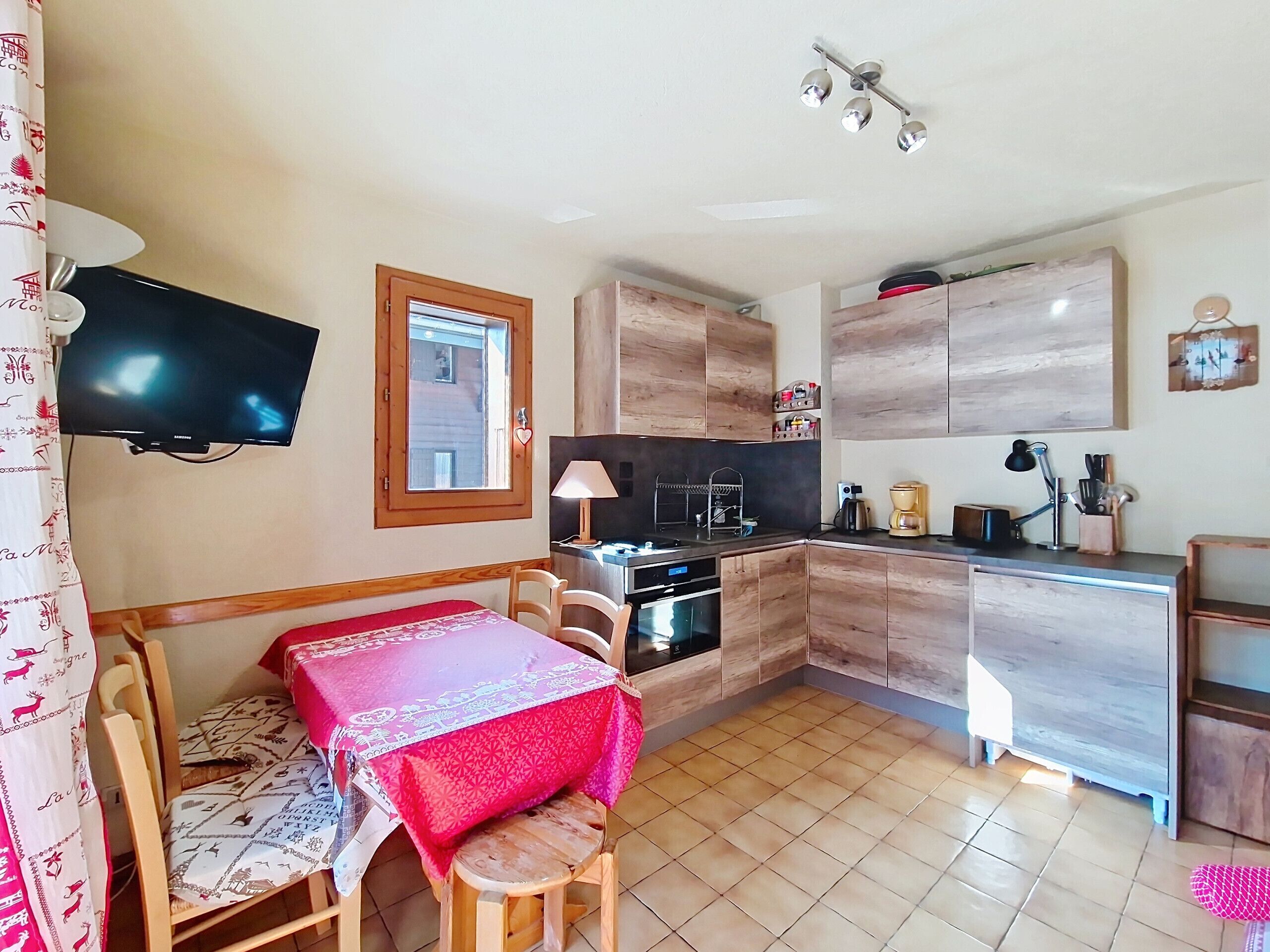 Una cucina compatta con mobili in legno, un forno integrato e una macchina da caffè.