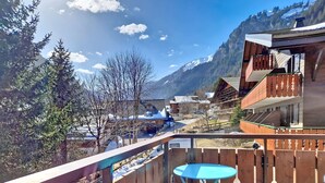 Ein Balkon mit Holzbalkon, einem kleinen blauen Tisch und einem Stuhl.