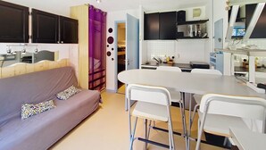 A compact room with a bed, a dining table with chairs, a kitchenette, and a bathroom with a shower. - Campanules CP6 TELECABINE & NATURE 4 Pers (Châtel)