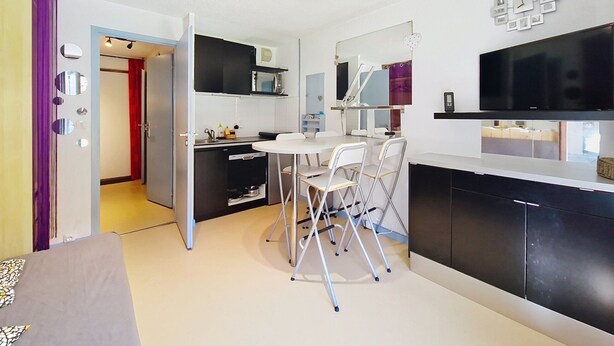 A modern kitchen with a dining area, a TV, and a mirror. - Campanules CP6 TELECABINE & NATURE 4 Pers (Châtel)