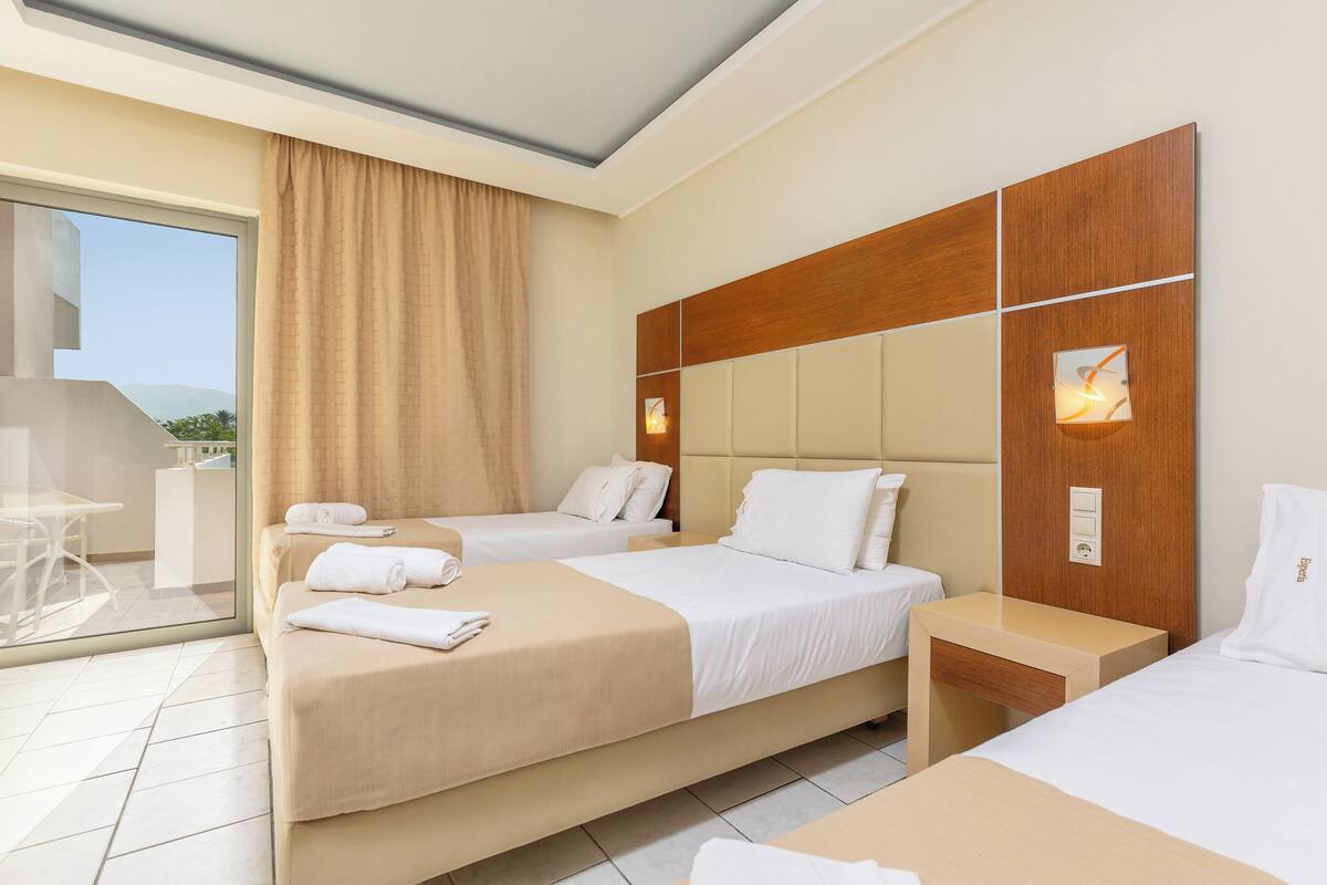 A hotel room with two beds, a large window with a view, and a balcony.