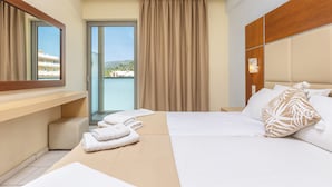 Habitación de hotel con cama, mesita de noche, espejo y vistas al exterior.