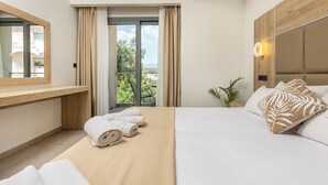 Una habitación de hotel moderna con una cama grande, cabecera de madera, mesita de noche, espejo y vistas al exterior.
