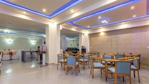 Un hall de hotel espacioso con iluminación moderna, una zona de recepción y varios conjuntos de asientos.