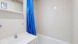 Un baño con lavamanos blanco, bañera y cortina de ducha azul.