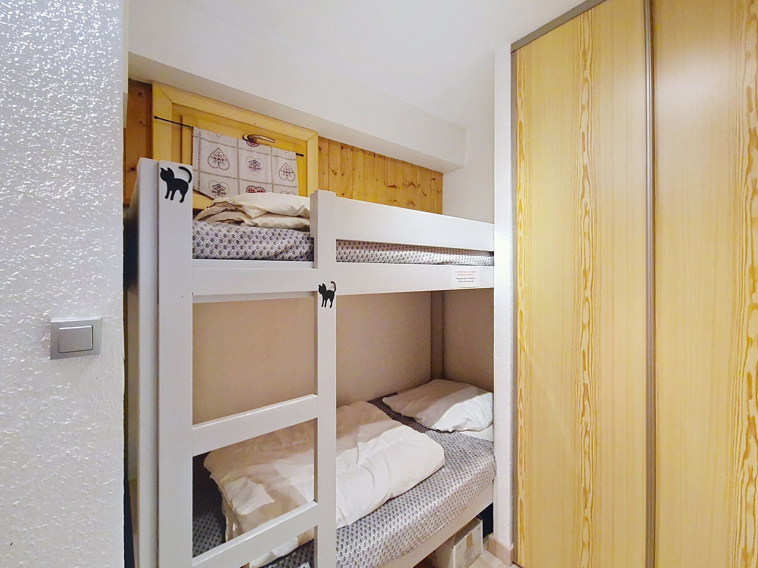 Un letto a castello con un poggiatesta in legno e un armadio con finitura in legno.