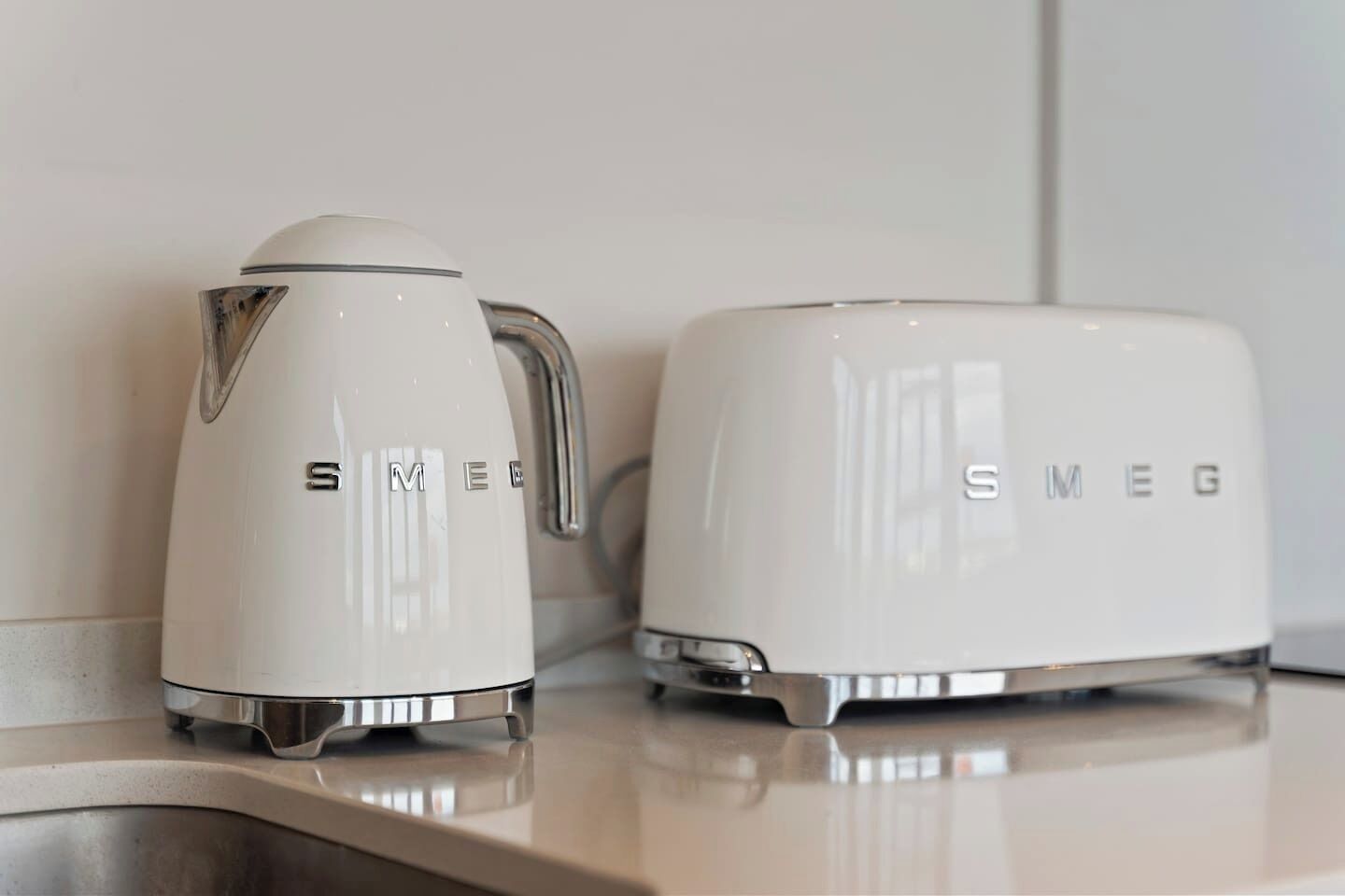 Two white kitchen appliances, a coffee maker and a toaster, on a countertop.