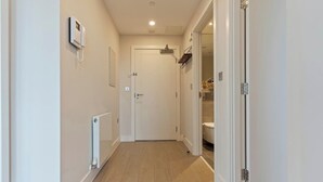 Un couloir étroit, avec une porte blanche au fond, qui donne sur une salle de bain.