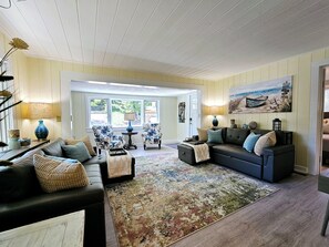 A spacious living room with a large window, a fireplace, and a cozy seating area. - Vintage charm, modern comfort! Lakeshore retreat 3 mins to the beach! (Muskegon)