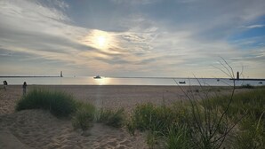 A beach with sand, grass, and a calm sea. - Vintage charm, modern comfort! Lakeshore retreat 3 mins to the beach! (Muskegon)