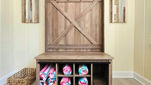 A wooden bench with a cross-back design, a woven basket, and colorful blankets. - Vintage charm, modern comfort! Lakeshore retreat 3 mins to the beach! (Muskegon)